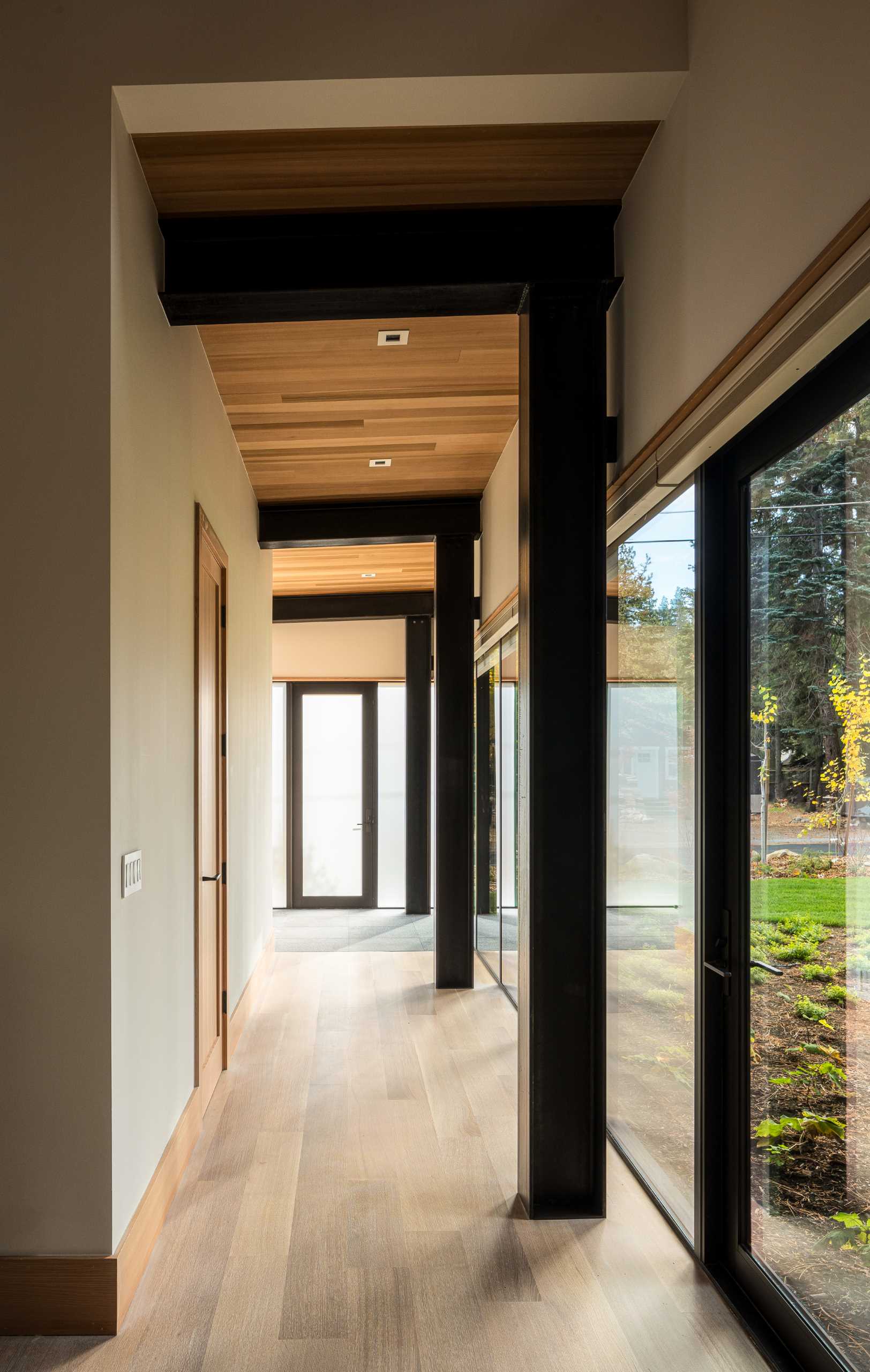 A hallway in this modern home is flooded with natural light from the windows that line it.