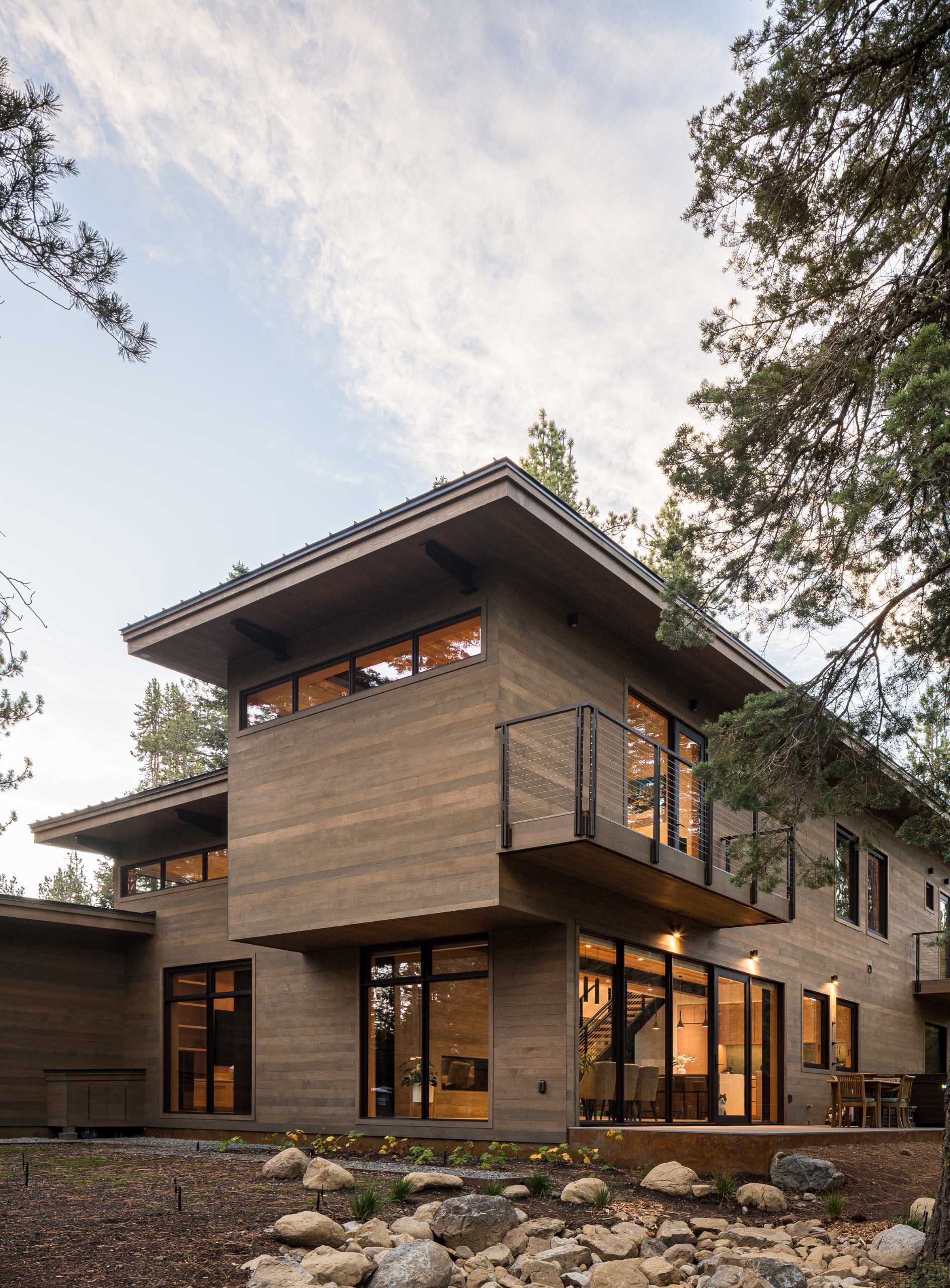 A modern home has an intentionally muted yet refined palette of natural materials including cedar, oak, fir, and steel, allowing the house to harmoniously blend with the surroundings.