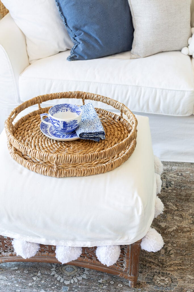 round woven tray on white slipcovered ottoman