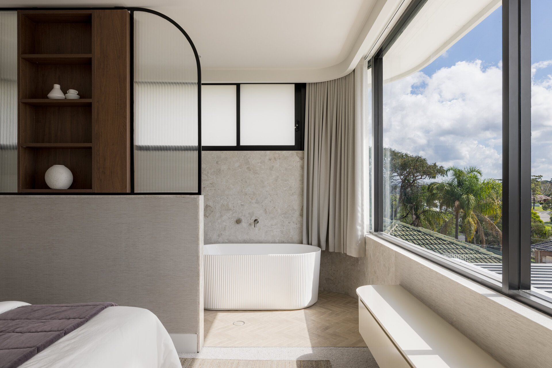 A modern bedroom with an open ensuite bathroom.