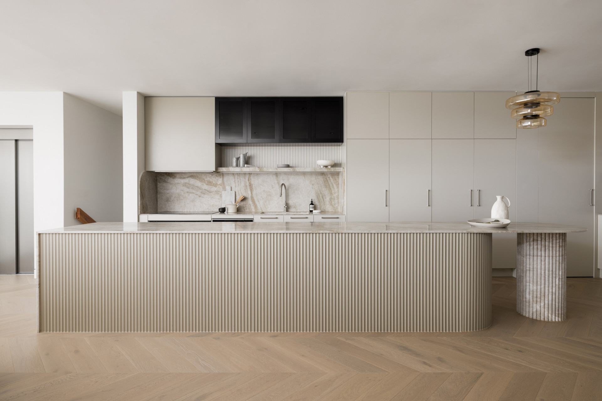 This modern kitchen has a large island with a fluted detail. The light and warm color tones chosen by the client to provide a tranquil and calming environment.
