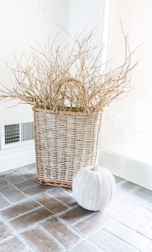 Tall handled basket with stone pumpkin in front of it.