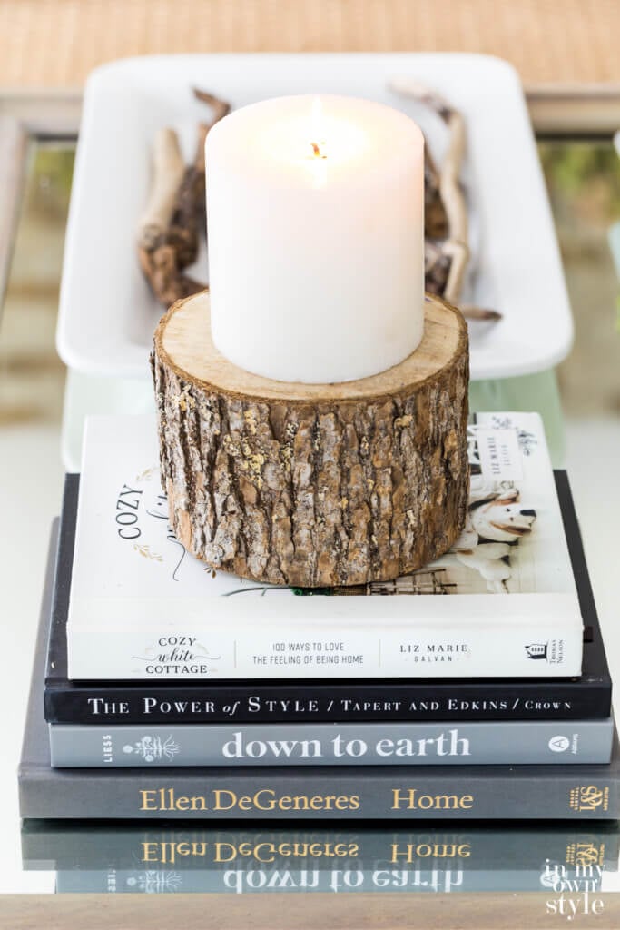 Books and candle on cut round a tree trunk on a coffee table.