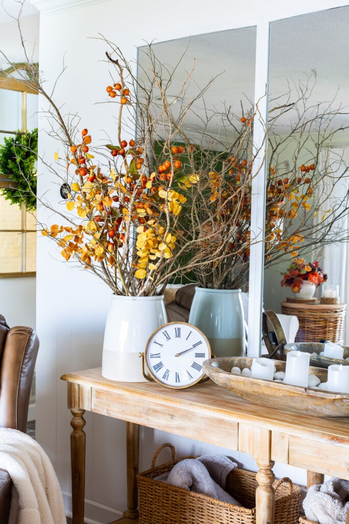 Bare wood sideboard with dried leaves and branches in large planter.