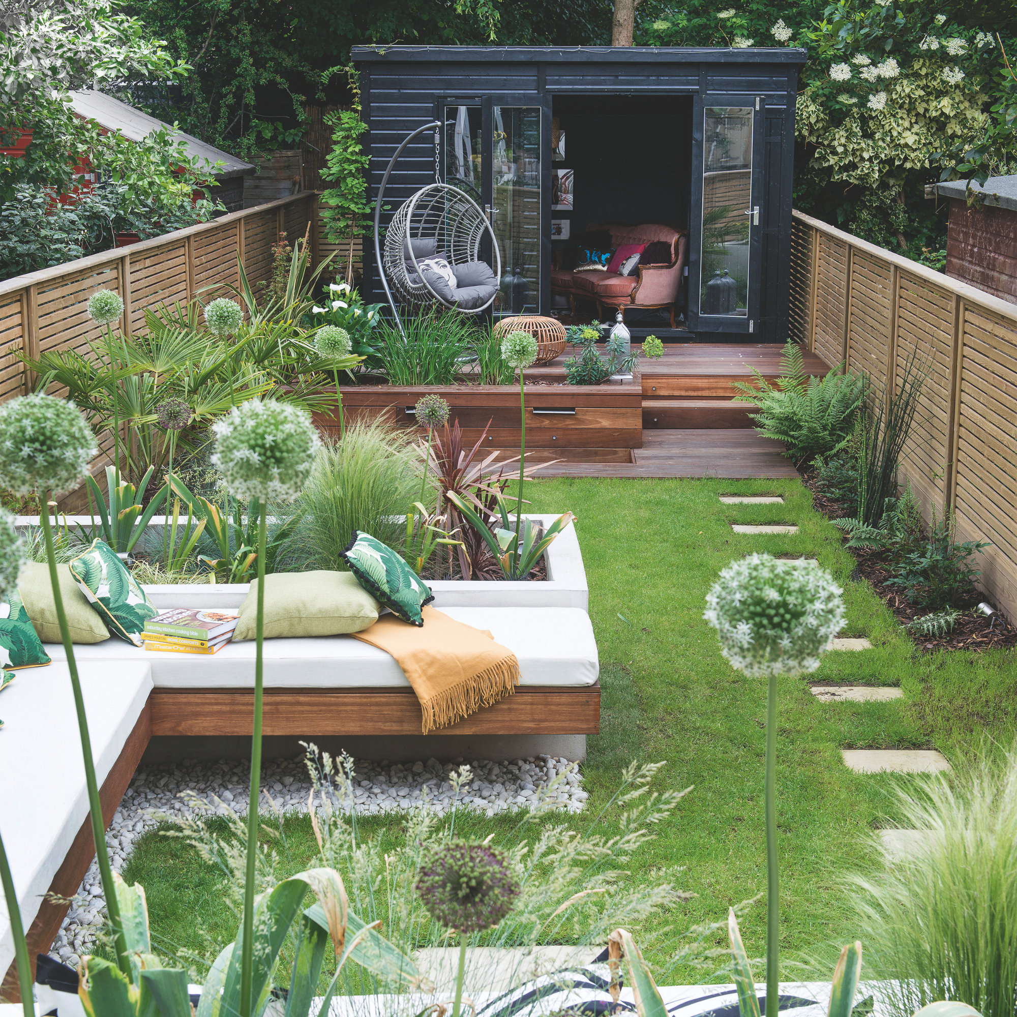 View down the garden with seating area and raised beds, wooden workshop at the end of the garden. The garden of a four bedroom Victorian house in North London, home of Tracey James and Paul Roye and their three adult children.