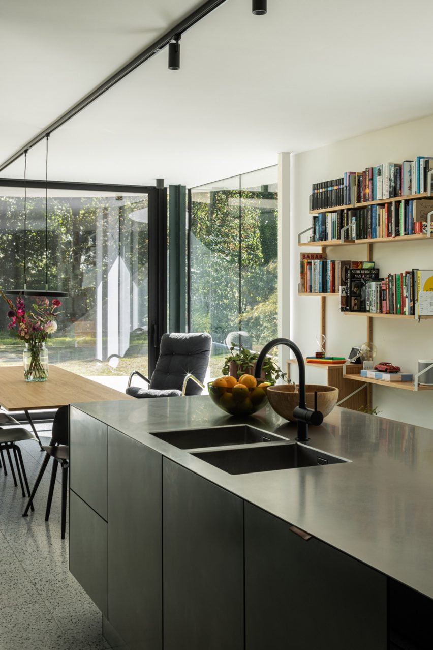 Stainless steel kitchen island and floating bookshelves inside The Garden Pavilion by Studio Okami